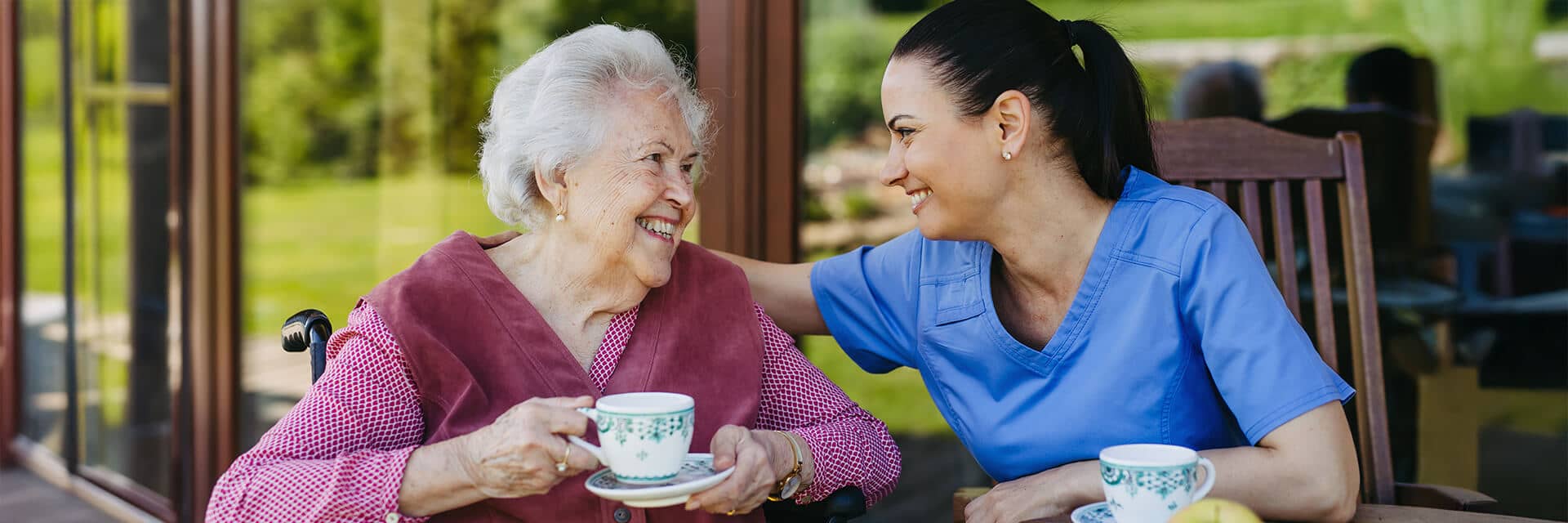 Nurse and resident chatting over coffee.